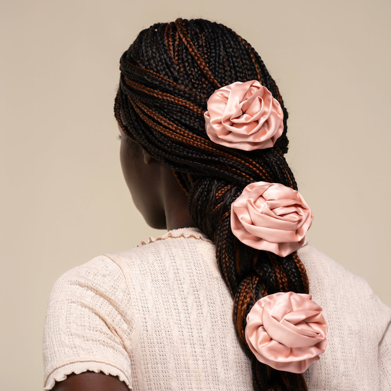 Person with braided hair adorned with terracotta rosette flat clips against a beige background