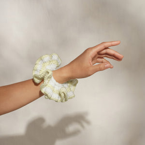 Model wearing KITSCH Coastal Cottage Butter Yellow Crochet Scrunchie on wrist against a neutral background