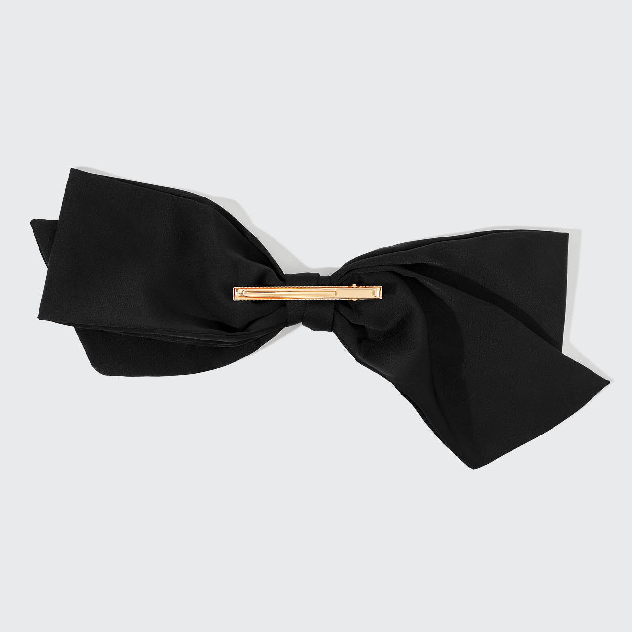 Black bow tie with a gold clasp on a light gray background